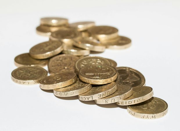 A pile of gold-colored coins scattered on a white surface. UK Benefit Reform: What It Means for Scotland